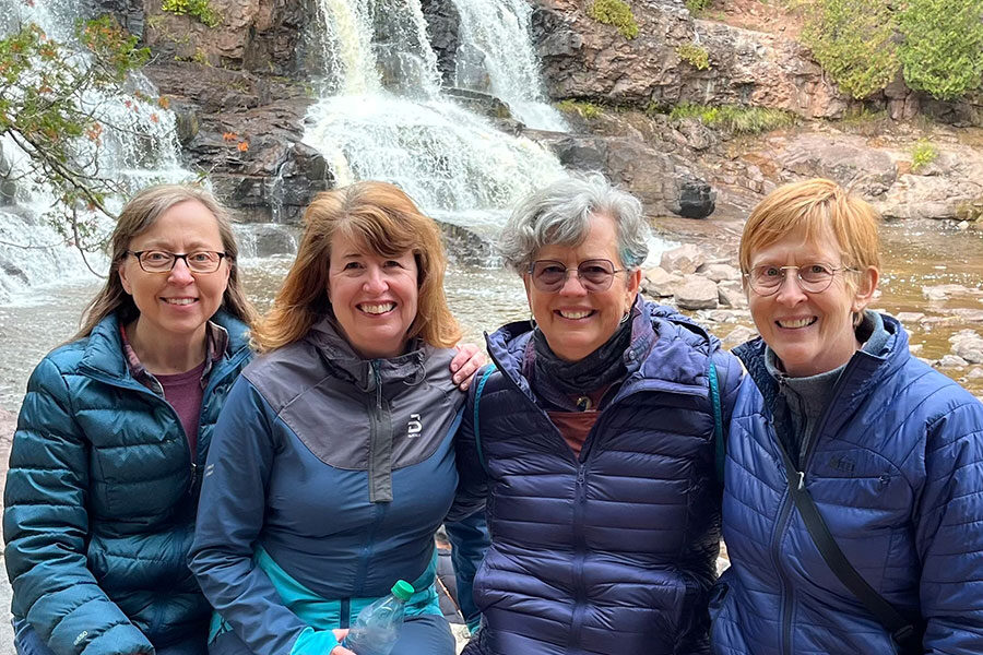 Four Luther alumna sitting in front of a waterfall