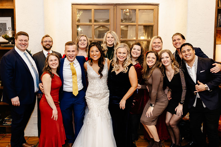 A large group of Luther alumni dressed formally, including a bride in a wedding dress, pose for a photo