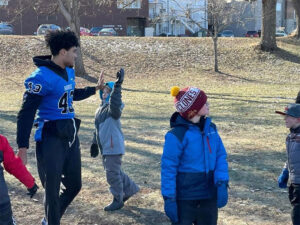 Photo of a Luther football player giving a high five to an elementary school student