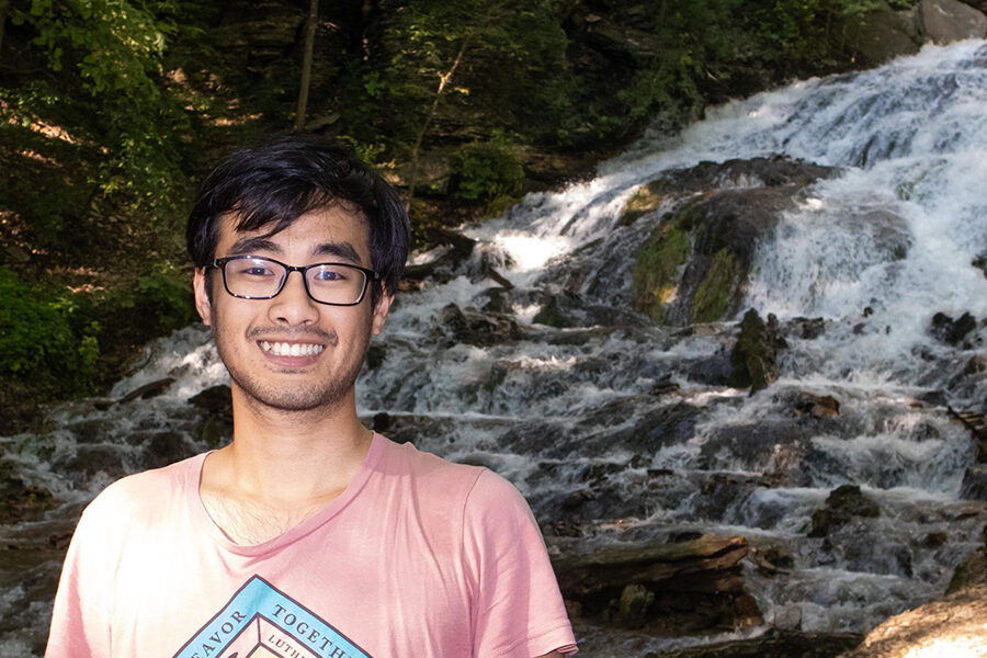 Minh smiles at the camera, and in the background is a waterfall.