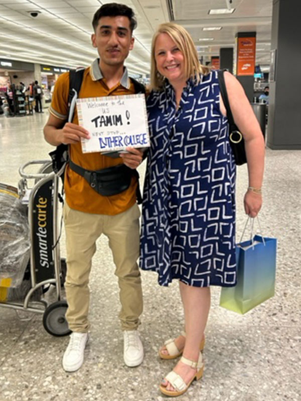 A man holding a handwritten sign stands next to a woman in an airport