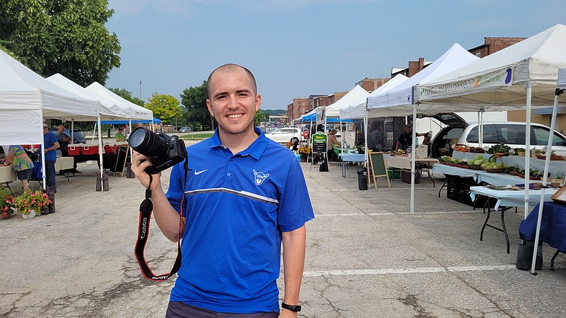 student capturing photos at local farmers market