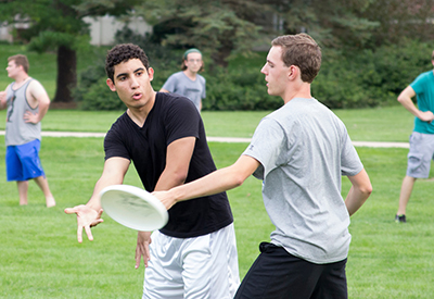 college students throw a frisbee on preus library lawn